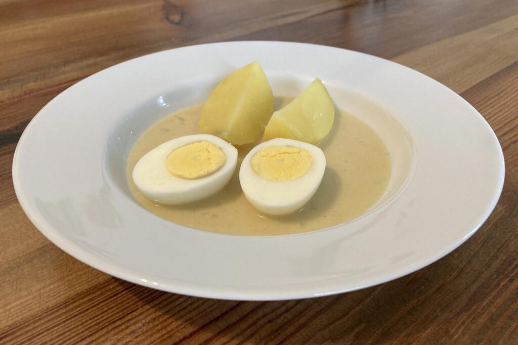 Hart gekochte Eier in süßsaurer Senfsoße mit Speck und Zwiebeln, dazu Salzkartoffeln
